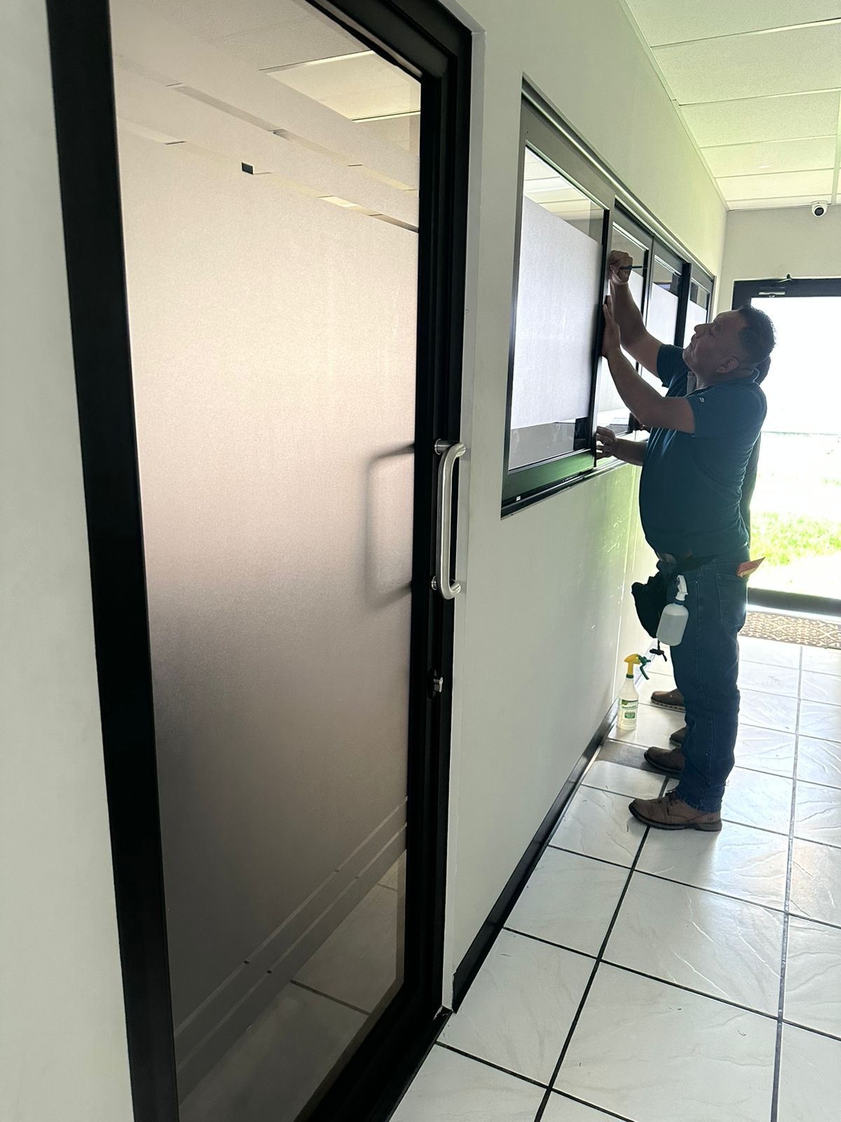 Técnico de SmartFilm instalando película nanocerámica en una ventana de oficina en San Salvador
